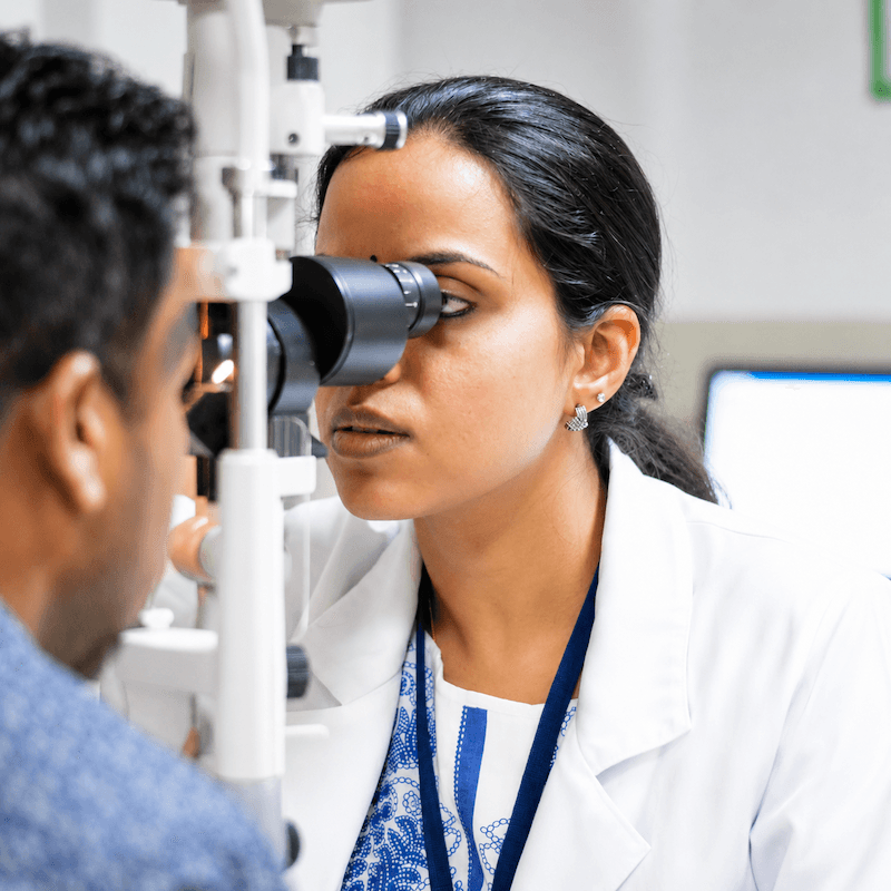 Eye specialist examining a patient with a slit lamp in a bright consulting room